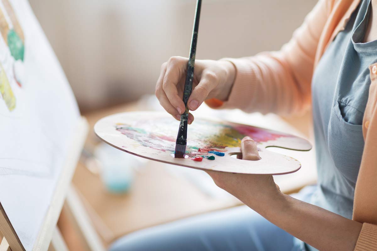 Adult holding painter's palette and paintbrush